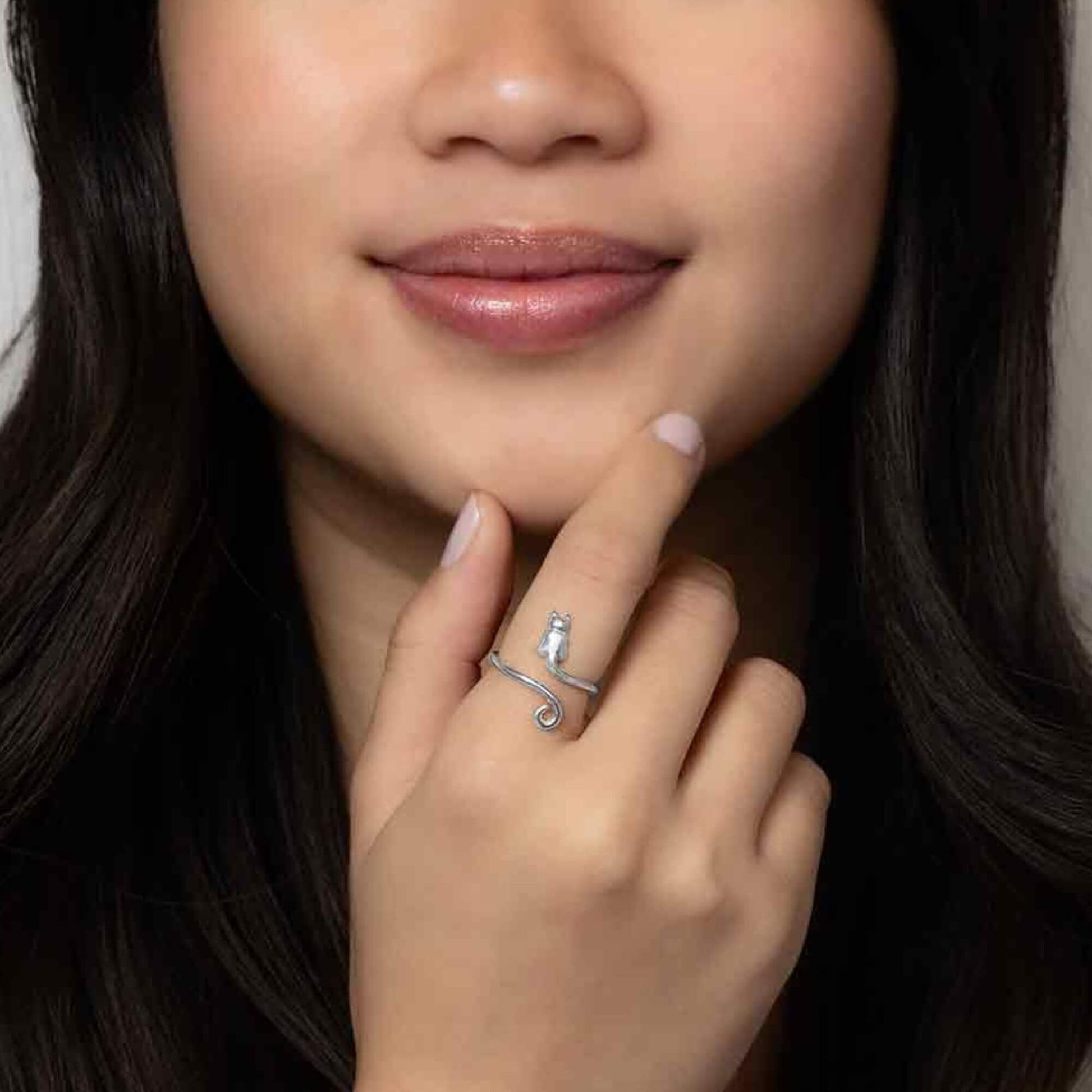A female model wearing our adjustable ring showing a dainty petite cat body with a swirly silver cat tail. 