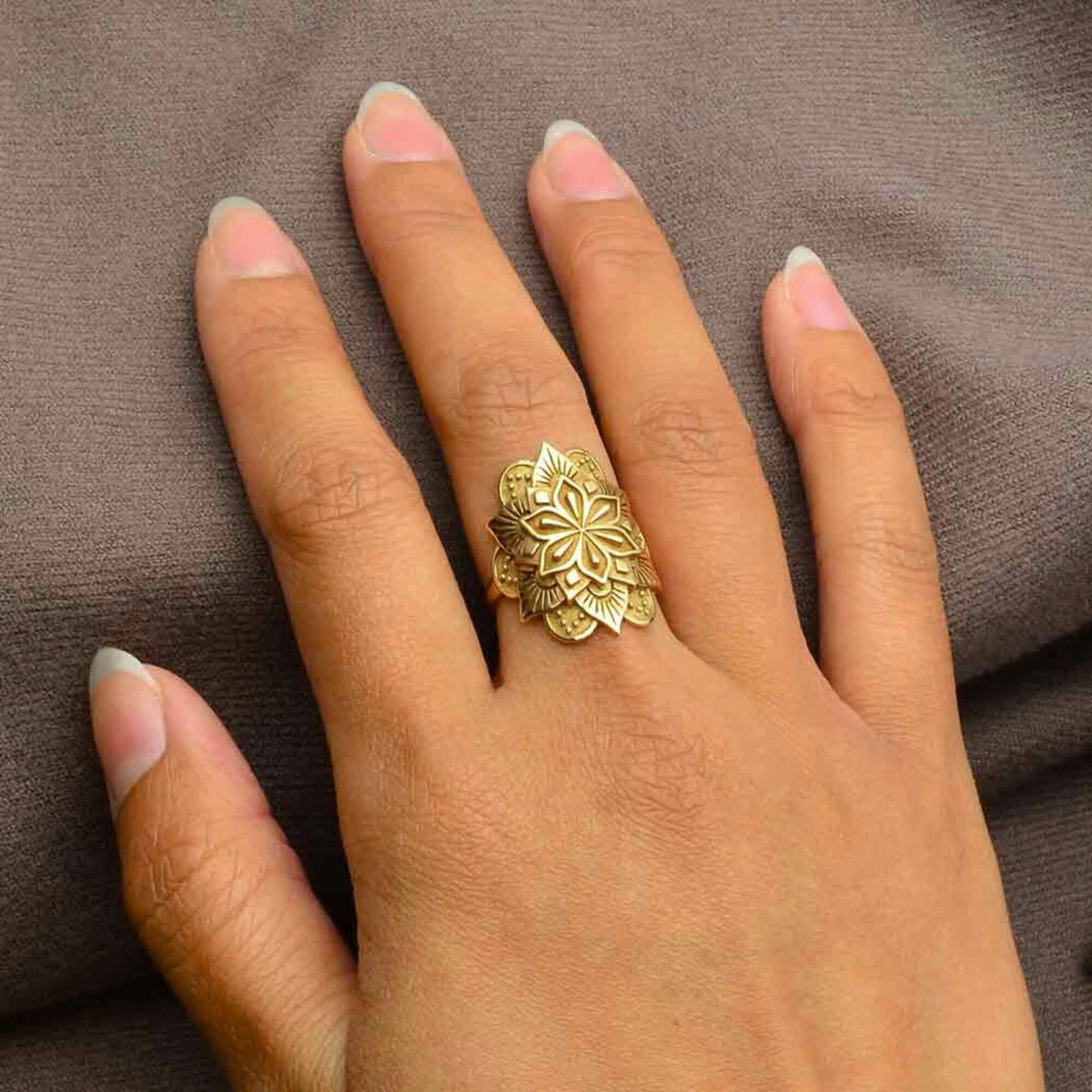 Hand showing the size of the gold mandala ring on a woman hand.  The mandala wraps around the finger and is wide and long. 