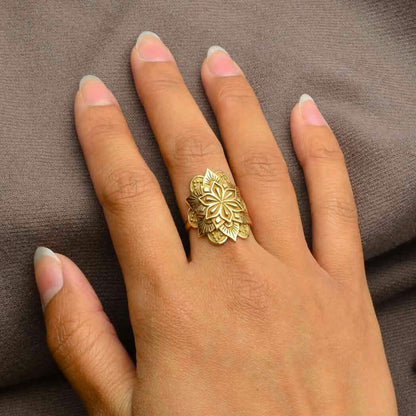 Hand showing the size of the gold mandala ring on a woman hand.  The mandala wraps around the finger and is wide and long. 